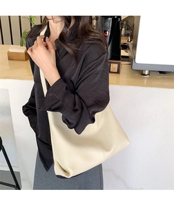 Close-up of beige lychee grain leather hobo bag worn by a model in a cafe setting