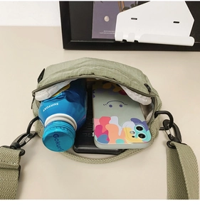 Top view of small green crossbody bag interior showing phone and water bottle capacity