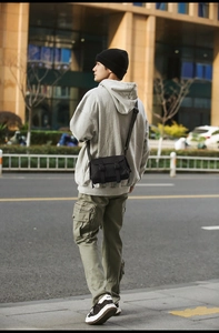 Street style shot of a black flap messenger bag paired with a city boy outfit