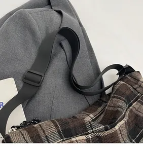 Dettaglio della tracolla regolabile in nylon nero sulla borsa tote a quadri marrone