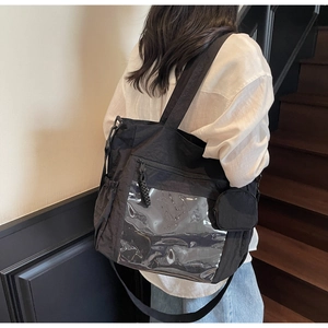 Detail of black nylon tote bag featuring a clear display window and a round coin purse