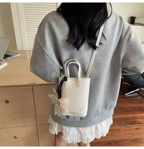 Vue arrière du mannequin portant un mini sac seau blanc avec breloque fleurie en tulle