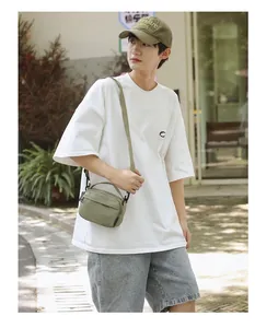 Olive green lightweight crossbody bag with adjustable strap worn by male model in nature