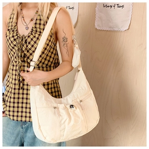 Detail der beigen Nylon-Sichelkappe mit Multi-Taschen-Design und kleiner hängender Geldbörse