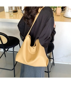 Rear view of a yellow lychee textured tote bag styled as a shoulder bag on a model