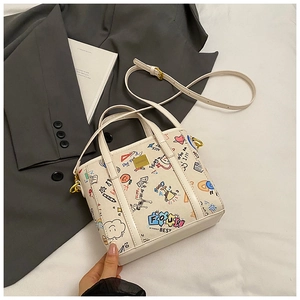 Detail view of white graffiti bucket bag with colorful patterns and golden metal hardware