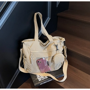 Detail view of beige nylon tote bag with transparent pocket and mini coin purse hanging