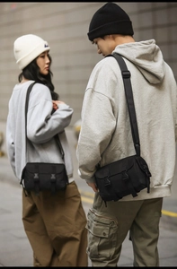 Outdoor street style shot of two models wearing the black messenger bag with flap closures