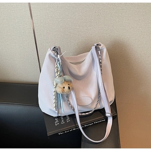 Detail of light purple PU leather tote bag with silver chain strap and a cute brown bear charm