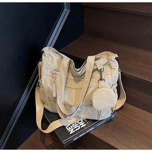 Close-up of beige nylon tote bag showing multiple zipper pockets and a mini coin purse