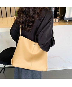 Close-up of yellow litchi grain leather tote bag with vertical stitching and metal buckle