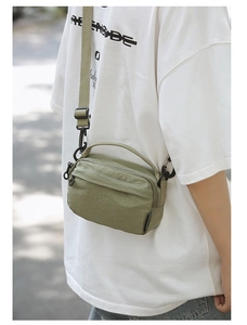 Detail of olive green textured crossbody bag worn by model in a street setting