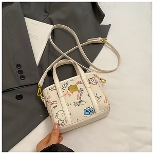 Close-up of white canvas bucket bag with colorful graffiti prints and gold hardware detail