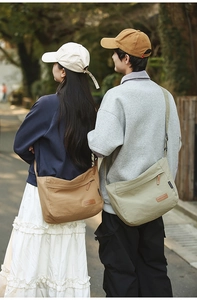 Brown and green large nylon messenger bags shown on models in a natural outdoor setting