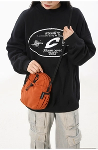 Détail de la sacoche bandoulière orange en nylon imperméable avec sangle noire