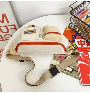 Détail du sac bandoulière en toile beige avec fermetures éclair orange et sangle