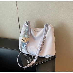 Detail of light purple pleated tote bag with silver chain and cute teddy bear charm