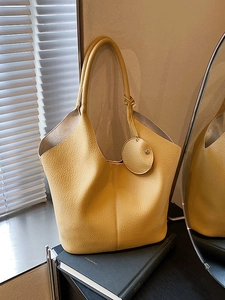 Chic yellow lychee pattern tote bag with round leather charm in a lifestyle setting