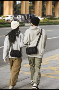 Outdoor shot of black messenger bags with dual buckle closure and nylon fabric