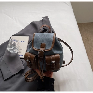 Detail of vintage denim plaid backpack with brown leather trim and metal buckles
