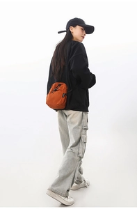 Détail du sac bandoulière orange étanche avec fermeture à cordon sur modèle