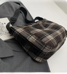 Dettaglio borsa a tracolla vintage a quadri marroni con tracolla regolabile su blazer grigio