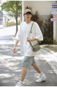 Detail of olive green nylon crossbody messenger bag on a summer street fashion outfit