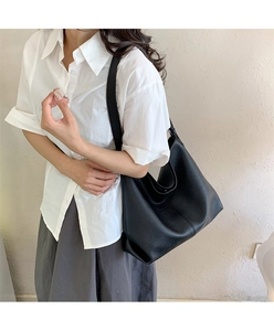 Detail of black pebbled leather tote bag showing large capacity and soft texture on model