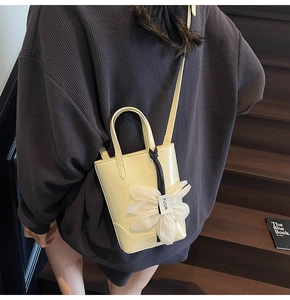 Détail d'un sac bandoulière crème avec une grande fleur en gaze blanche et une lanière