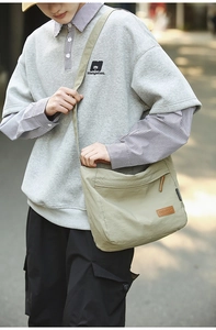 Detail of khaki water-resistant nylon messenger bag with brown leather brand tag