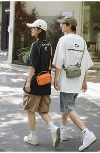 Outdoor street style shot of compact orange and olive green nylon crossbody bags with handles