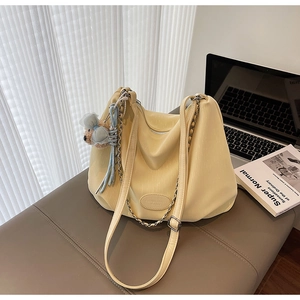 Detail of beige soft leather tote bag with chain strap and cute bear charm accessory