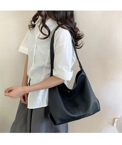 Close-up of black lychee grain leather hobo bag showing texture and wide shoulder strap