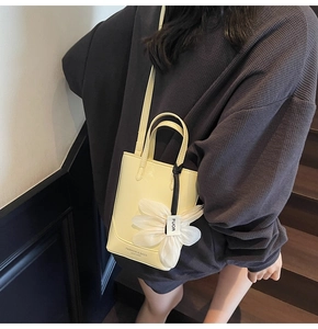 Détail du mini cabas jaune crème avec breloque fleurie marguerite et finition en cuir