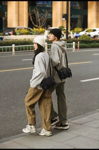 Outdoor street shot of black nylon messenger bag with buckle for men and women