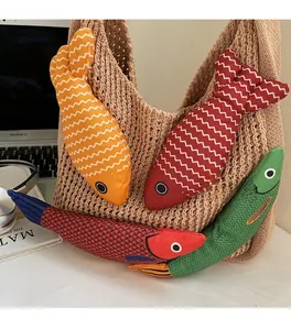 Detail of colorful fish-shaped fabric charms tucked into a beige crochet tote bag