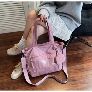 Detail of mauve nylon tote bag featuring front zipper pocket and round detachable coin purse