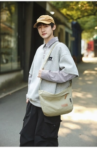 Detail of water-resistant nylon messenger bag with brand label and flap closure