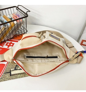 Détail du sac de poitrine en toile crème montrant la poche intérieure zippée