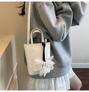 Détail du mini sac seau blanc avec texture en cuir et breloque fleur en mousseline