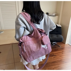 Detail of dusty pink nylon tote bag showing multiple zipper compartments and small pouch