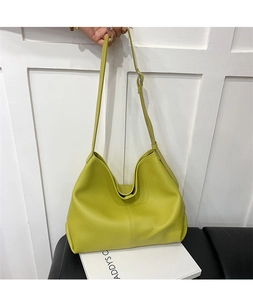 Detail of lime green shoulder bag with lychee grain leather texture and saddle shape