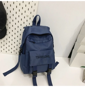 Detail of navy blue canvas backpack featuring TIANFLONG embroidery and front flap pocket