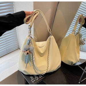 Detail of creamy yellow tote bag with silver chain and cute blue bow bear charm