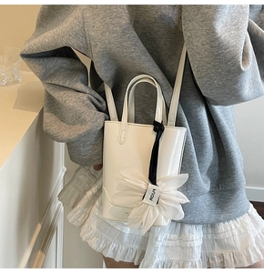 Détail du sac seau en cuir blanc avec une grande fleur en organza et bandoulière