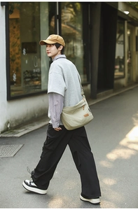 Outdoor street style model carrying a large waterproof nylon messenger bag in olive green