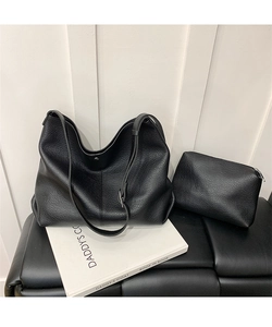 Close-up of black lychee grain leather hobo bag and matching zippered pouch on leather stool