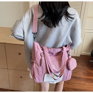 Detailed view of pink nylon tote bag with transparent front pocket and side storage pouch