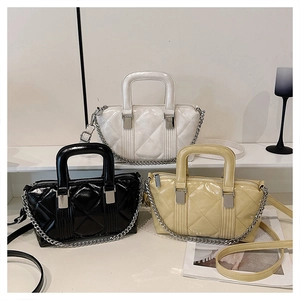 Close-up of quilted tote bags in white, black, and yellow with silver chain straps