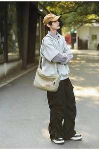 Outdoor shot of a khaki nylon crossbody bag featuring a leather patch and brand tag